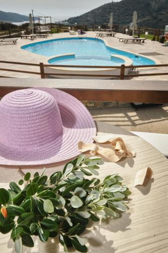 a pink hat sitting on a table near a swimming pool at Amorgion Village in Katapola