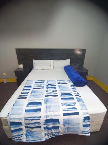 a bed with a blue and white blanket on it at Prime Guest Inn in Benoni