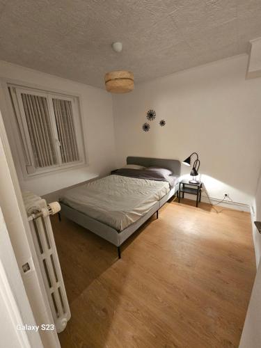a bedroom with a bed and a wooden floor at La Maison cosy de ville 3 chambres in Marly