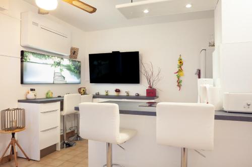 a room with white chairs and a flat screen tv at Studio proche des plages in Le Pradet