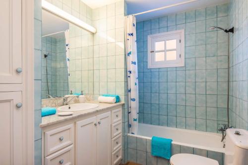 La salle de bains est pourvue de carrelage bleu, d'un lavabo et de toilettes. dans l'établissement Villa Can Bolduc by Villa Plus, à Cala en Blanes