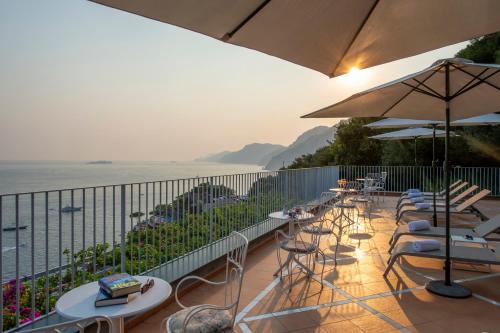 a balcony with chairs and tables and an umbrella at Il Barilotto in Positano
