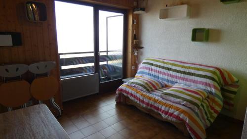1 cama con manta a rayas en una habitación con ventana en Studio Yeti Immobilier, en Thollon-les-Mémises