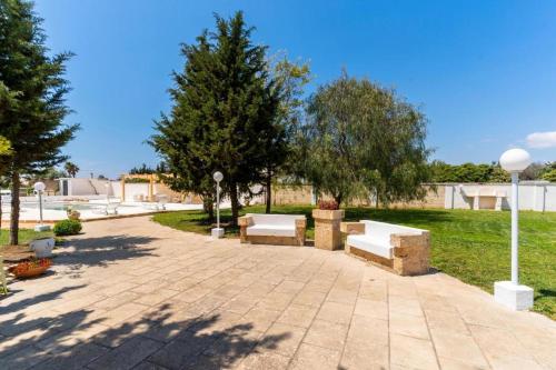 a park with benches and trees on a sidewalk at Villa Dei Lidi - HomeSalento com in Torre San Giovanni Ugento