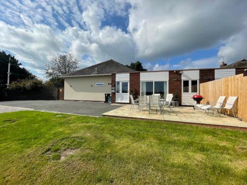 a house with a patio with chairs and a fence at The Ridge Bungalow, at the highest point in the Heart of Cheshire in Frodsham