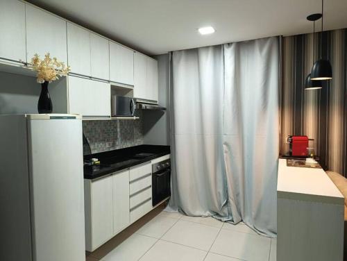 uma cozinha com armários brancos e um frigorífico em Stay GRU - Loft Completo próx GRU airport - Guarulhos em Guarulhos