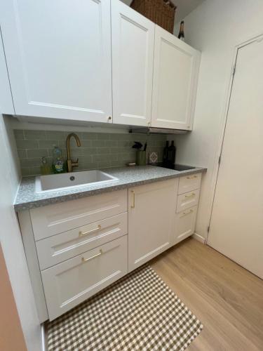 Charming and cozy apartment in Pantin في بانتين: مطبخ مع دواليب بيضاء ومغسلة