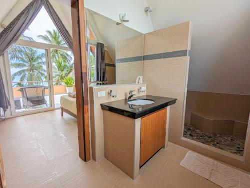 een badkamer met een wastafel en een bad met een raam bij Beachfront 5-bedroom Villa in Ko Chang