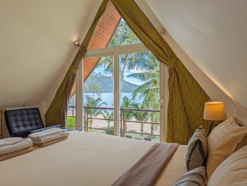 ein Schlafzimmer mit einem großen Fenster mit einem Bett und einem Stuhl in der Unterkunft Beachfront 5-bedroom Villa - by KohChangVillas in Ko Chang