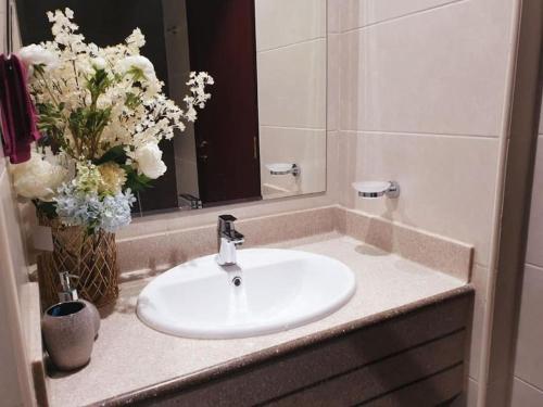 a bathroom sink with a mirror and a vase of flowers at LuxeHome where blue sea & white sands greets you in Ajman