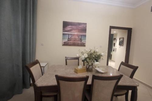 a dining room with a table with chairs and a painting at LuxeHome where blue sea & white sands greets you in Ajman