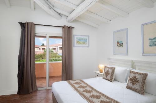 a white bedroom with a bed and a balcony at VOI Colonna Village in Golfo Aranci