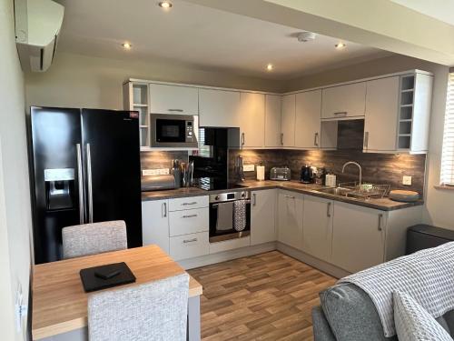 a kitchen with white cabinets and a black refrigerator at Loanside Lodge, Self-Catering, Holm, Orkney. in Saint Marys