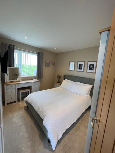 a bedroom with a large white bed and a desk at Loanside Lodge, Self-Catering, Holm, Orkney. in Saint Marys