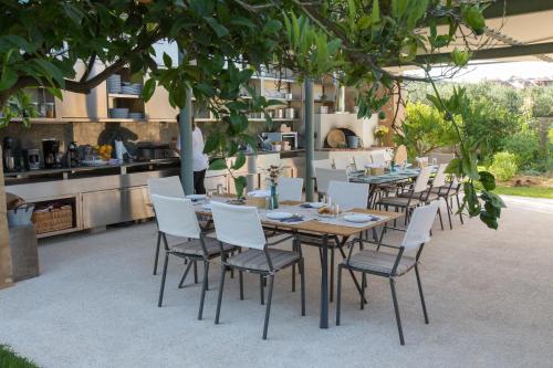 a table with white chairs and a table and a kitchen at Conte Marino Villas in Maleme
