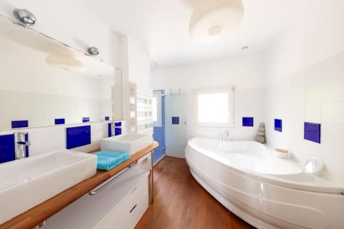 La salle de bains blanche est pourvue de 2 lavabos et d'une grande baignoire. dans l'établissement Villa Canopia - Villa with swimming pool Capbreton, à Capbreton