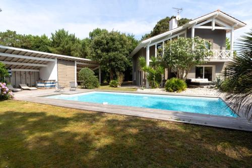 une maison avec une piscine devant une maison dans l'établissement Villa Canopia - Villa with swimming pool Capbreton, à Capbreton