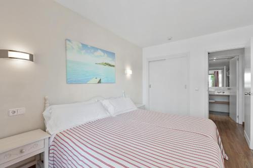 Apartamentos Pabisa Orlando في بلايا ذي بالما: غرفة نوم بيضاء مع سرير و لوحة على الحائط