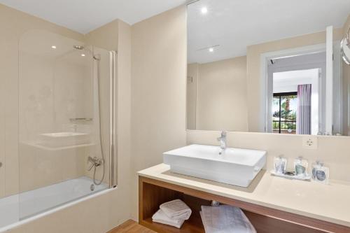 ein weißes Bad mit einem Waschbecken und einer Dusche in der Unterkunft Apartamentos Pabisa Orlando in Playa de Palma