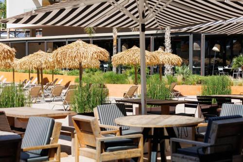 an outdoor patio with tables and chairs and straw umbrellas at Hotel Aubamar Suites & Spa in Playa de Palma