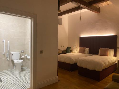 um quarto com 2 camas e uma casa de banho com WC. em Markree Courtyard em Collooney