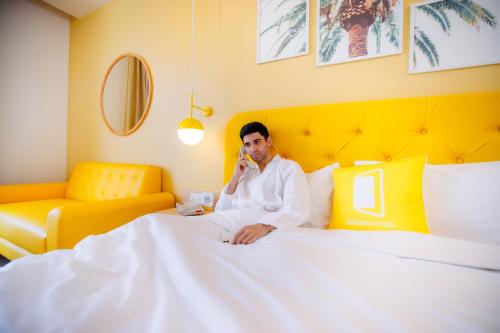 a man sitting on a bed talking on a cell phone at Bloom Hub - ORR Marathahalli in Bengaluru