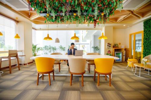 a man sitting at a table with a laptop at Bloom Hub - ORR Marathahalli in Bengaluru