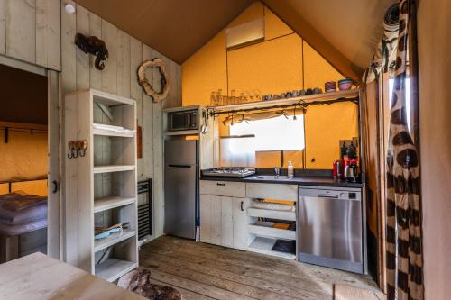 a kitchen with a stove and a sink in it at Camping Vossenberg - op de Veluwe! in Epe