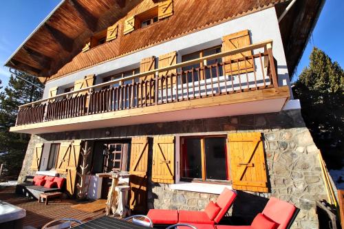 Casa con balcón y terraza con sillas rojas. en Spacious Chalet 16/18 Guests w/Slope View, Jacuzzi et Sauna, en Montgenèvre
