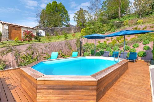 une piscine avec une terrasse en bois avec des chaises et un parasol dans l'établissement Gîte du Thouet - Appt avec piscine partagée, à Montreuil-Bellay
