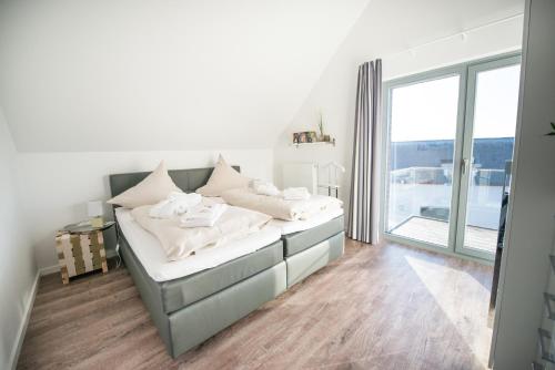 ハイリゲンハーフェンにあるOstsee - Appartement Nr 65 "Seaside" inkl Strandkorb im Strand Resortのベッドルーム1室(ベッド1台、大きな窓付)