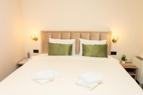 a bedroom with a large white bed with green pillows at Merak Rooms & Caffe Bar in Šabac