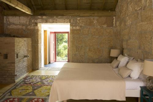 a bedroom with a bed in a stone wall at Casa Agricola da Levada Eco Village in Vila Real