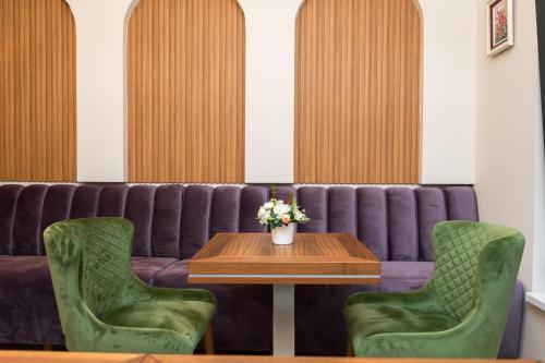 2 sedie verdi e un tavolo con un divano viola di Merak Rooms & Caffe Bar a Šabac
