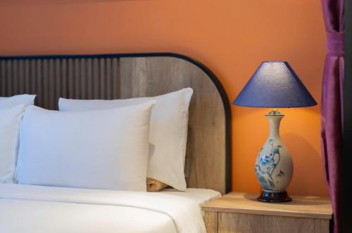 a bed with a blue and white vase on a table with a lamp at Aaron Boutique Hotel in Nha Trang
