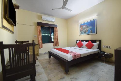 Schlafzimmer mit einem Bett mit roten Kissen und einem TV in der Unterkunft OYO 24408 Nirmala Guest House in Jodhpur