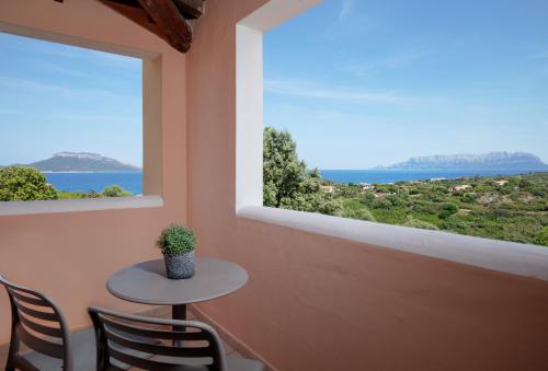 a table and chairs in a room with a large window at VOI Colonna Village in Golfo Aranci