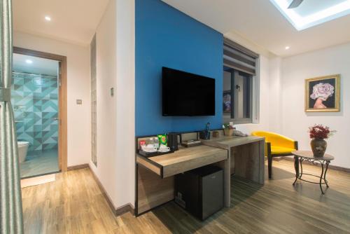 a room with a blue wall with a desk and a television at Aaron Boutique Hotel in Nha Trang