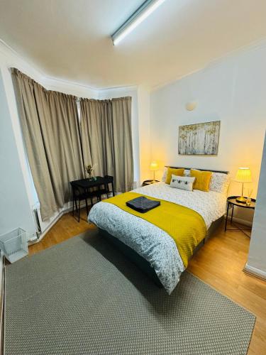 a bedroom with a large bed with a yellow blanket at 2 Bedrooms House near Central London in London