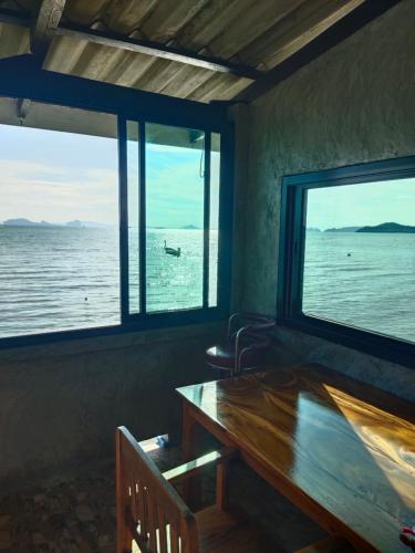 une chambre avec une table et deux grandes fenêtres dans l'établissement Poohry Seaview, à Ko Lanta