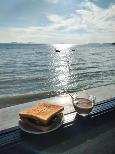 a sandwich on a plate next to a bowl of sauce at Poohry Seaview in Ko Lanta