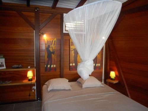 a bedroom with a bed with a white mosquito net at Ti Chalet à Malendure Bouillante in Bouillante