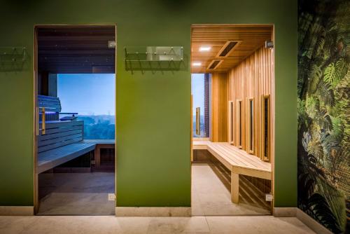 a green room with a bench and a window at Van der Valk Hotel Enschede in Enschede