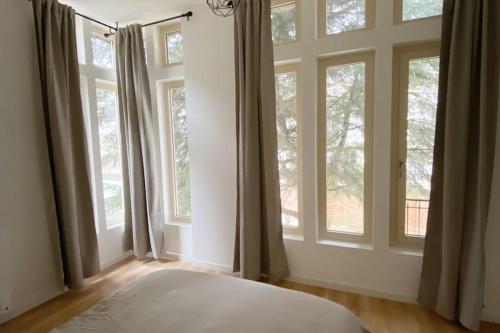 - une chambre avec de grandes fenêtres et un lit blanc dans l'établissement Appartement coup de coeur en centre-ville, à Orléans