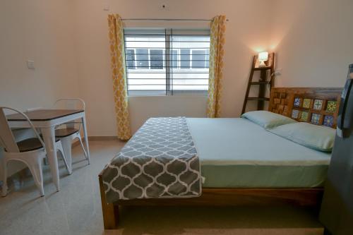 a bedroom with a bed and a desk and a window at HomeSlice Manzil - 1BHK in HSR in Bangalore