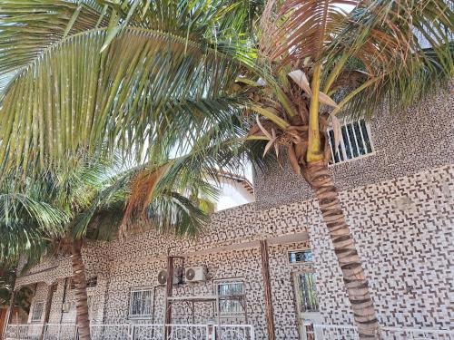 two palm trees in front of a brick building at La Mboroise in Mboro