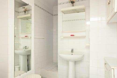 Baño blanco con lavabo y espejo en Studio proche des plages, en Le Pradet