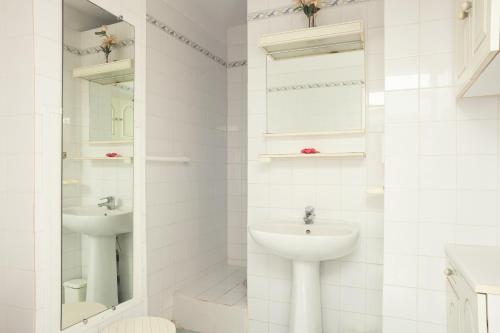 a white bathroom with a sink and a mirror at Studio proche des plages in Le Pradet