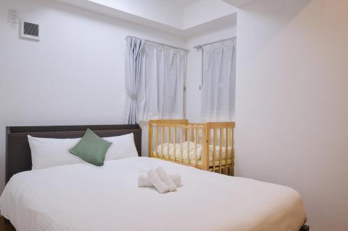 a bedroom with a white bed and a crib at Coral Gate in Kume コーラルゲートイン久米 in Naha