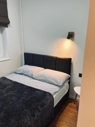 Bett mit schwarzem Kopfteil in einem Zimmer in der Unterkunft Sun Clock Apartment in Šiauliai